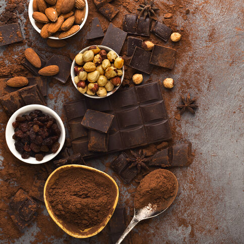 Rozdrvené kúsky čokoládovej tyčinky a kakao na sivom pozadí, pohľad zhora
